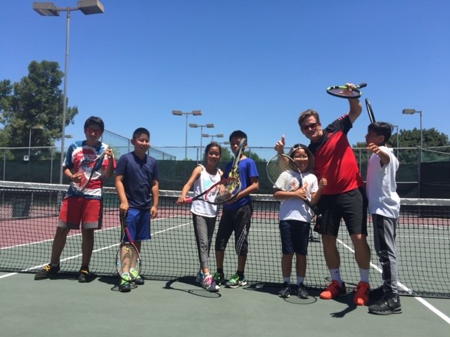 Jimmy Gleason on court with a small group of junior players holding rackets