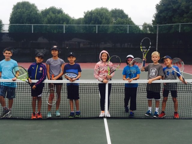 Junior tennis camp group gathered at the net