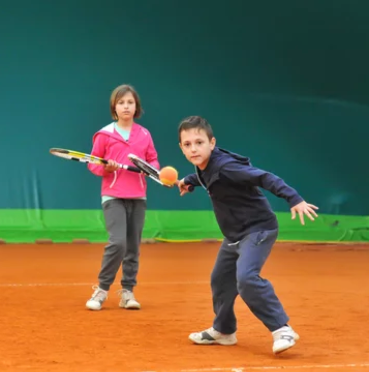 Children participating in a tennis lesson on court