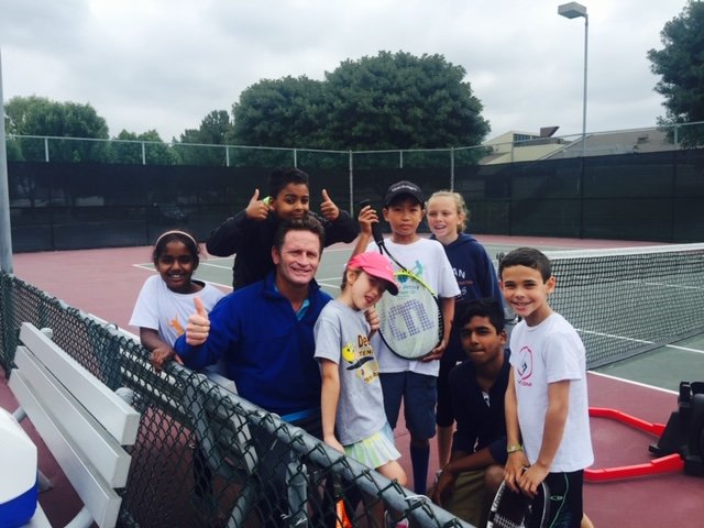 Tennis coach working with a group of students on court